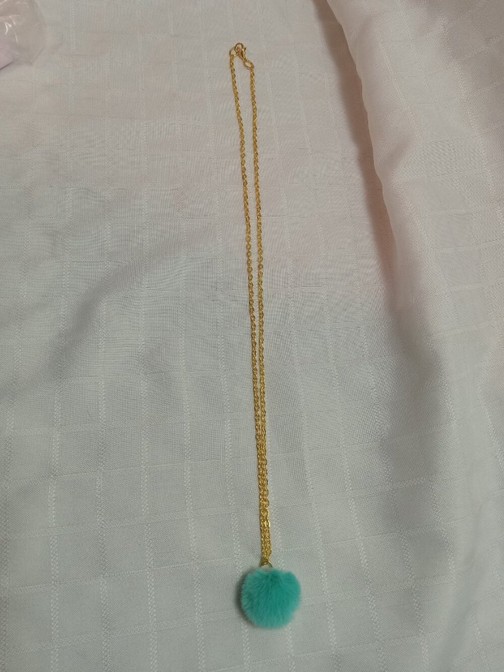 Handmade necklace with a small pom-pom and gold-colored accent hooks & chains